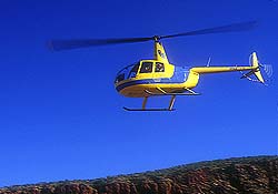 Gelber Hubschrauber vor stahlblauem Himmel in Glen Helen